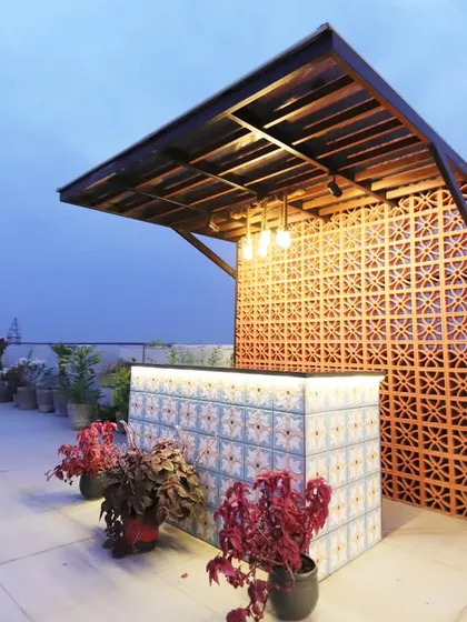 The bar area illuminated at dusk, highlighting the intricate terracotta screen and the warm glow from the under-counter lighting.