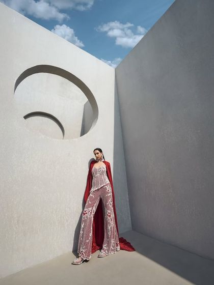 A fully pearl-embellished corset paired with tailored pants. The look is elevated by a floor-sweeping crushed cape that doubles as a dramatic choker, defining elegance with an edge.