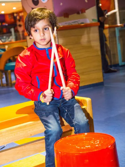 A young rockstar with drumsticks, finding creative ways to play during his unlimited thrills session.