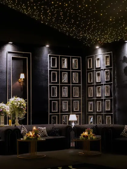 Another angle of the monochrome lounge, highlighting the curated photo gallery walls and the warm glow of classic wall sconces against the dark, textured backdrop.