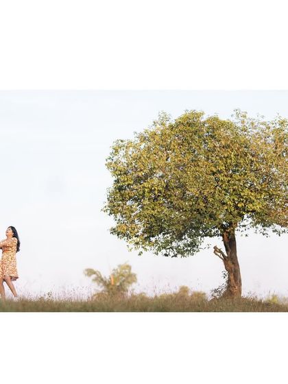 A wide, cinematic shot of the couple holding hands under a lone tree, creating a feeling of a world that is all their own.