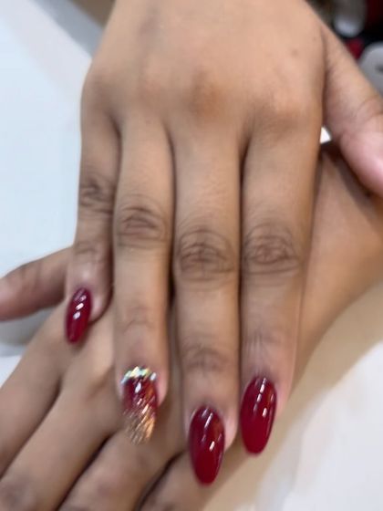 A close-up of the gold glitter gradient and rhinestone placement on this elegant red nail set.
