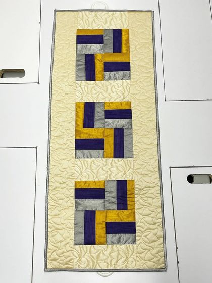An elegant table runner made from silk fabric in a geometric pattern.