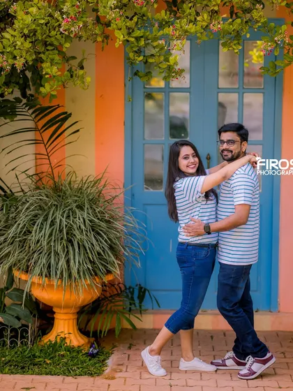 A playful and happy couple in matching outfits against a colorful wall, showcasing the fun and vibrant backdrops we offer.