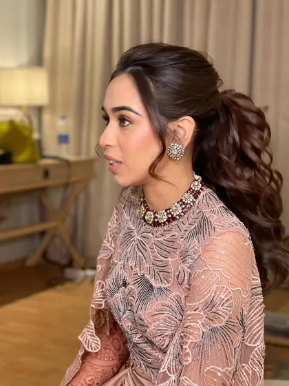 A portrait of a bride with a curly, high ponytail for her cocktail party. The volume at the crown and the bouncy curls create a very glamorous look.