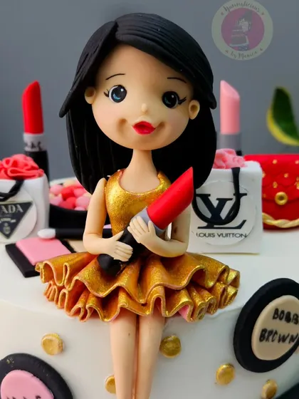A close-up of the girl figurine on a makeup and shopping themed cake, holding a bright red lipstick.