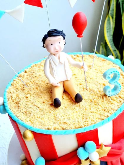 A close-up of the hand-sculpted boy figurine on the carnival cake.