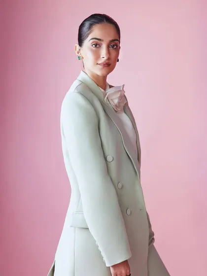 A side profile of Sonam Kapoor in her elegant longline coat and pantsuit, highlighting the clean lines and sophisticated silhouette.