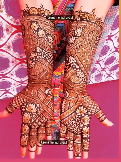 A beautiful example of a full bridal design with a rich, dark henna stain. The pattern features swirling paisleys and lotus flowers, with every inch of the hands and arms covered in detailed artwork.