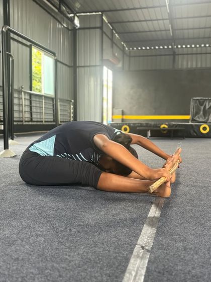 A student works on her forward fold, a fundamental stretch for hamstring flexibility.