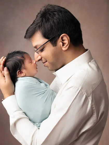 A father's gentle strength is on display as he holds his tiny newborn. The contrast in size highlights just how small and precious they are in these early days.