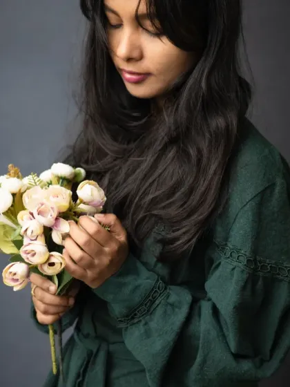 A soft and contemplative moment captured during a portrait session. The way she holds the flowers adds a touch of gentleness and introspection to this classic studio portrait.