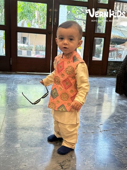 That smile, that swag, that outfit. This little NRI cutie looks adorable in our peach printed Bundi set during his visit to our store.