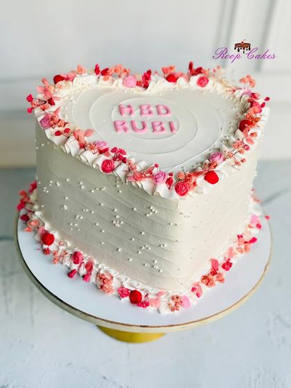 A heart full of love. This beautiful heart-shaped cake is decorated with a border of delicate pink and red sprinkles and flowers, making it a sweet and romantic gesture.