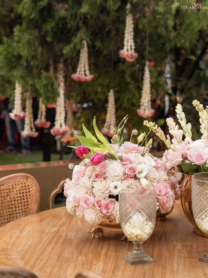 A tablescape detail showing a lush floral centerpiece complemented by traditional mogra flower hangings, blending modern and classic elements.