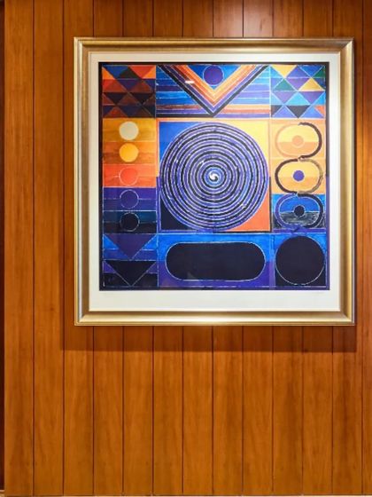 This abstract, geometric painting with its swirling central form and bold colors is a modern interpretation of spiritual art. Placed against a warm wood-paneled wall, it becomes a powerful focal point for meditation and energy.