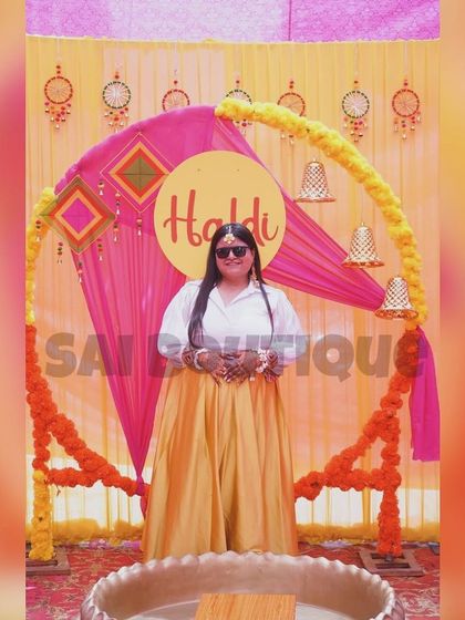 A happy client at her Haldi ceremony in a simple yet elegant yellow skirt and white shirt combination. It's a chic and comfortable choice.