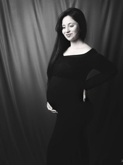 A candid, gentle smile. This black and white image captures a natural and happy moment, showing the quiet joy of pregnancy.