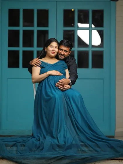 An intimate couple's portrait, with the flowing teal gown creating a beautiful frame. This is a perfect example of a romantic and stylish maternity photo.