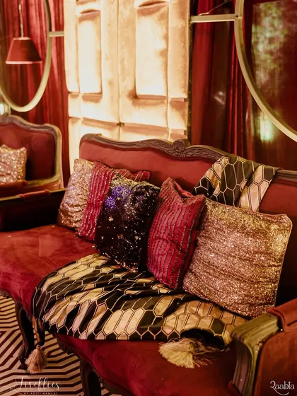 A luxurious lounge sofa at 'The Scarlet Soirée', adorned with sequined and velvet cushions in rich, dramatic tones.