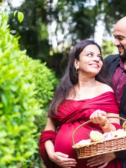 A sweet and classic maternity portrait. The couple looks at each other lovingly, with the mom-to-be holding a basket of flowers.