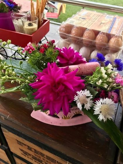 A beautiful spring-themed floral arrangement. The vibrant pink dahlia and fresh blooms bring a pop of colour and life to the table.