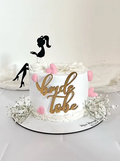 Perfect for a bachelorette party, this 'Bride to be' cake is fun and chic. It features a silhouette topper, a textured gown effect, and is decorated with little pink hearts and fresh baby's breath.