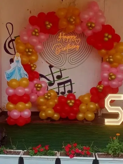 A close-up of a princess-themed birthday party I did in Noida. The setup includes a circular balloon arch, character cutouts, and a light-up number '5'.