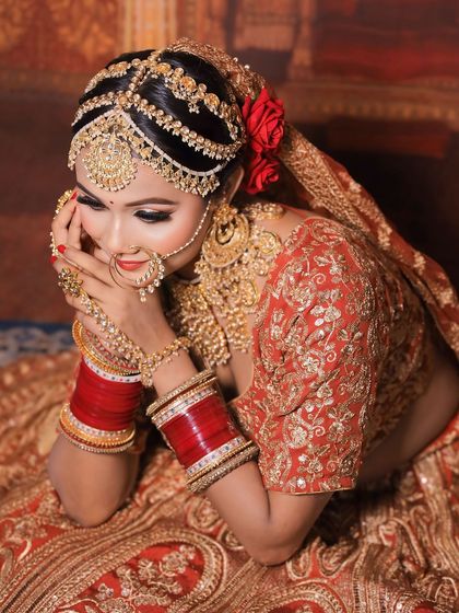 A candid, happy moment captured. The bride is wearing a full golden jewellery set and a beautiful red and gold lehenga.