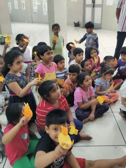 A group of young children proudly holding up the simple finger puppets they made during our 'Putani Shibira' workshop. It's amazing to see what they can create with just paper and their imagination.