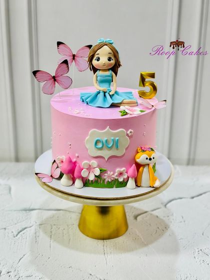 A pretty pink cake for Ovi's 5th birthday. This enchanted forest theme includes a custom doll, a friendly fox, pink mushrooms, and delicate butterflies.