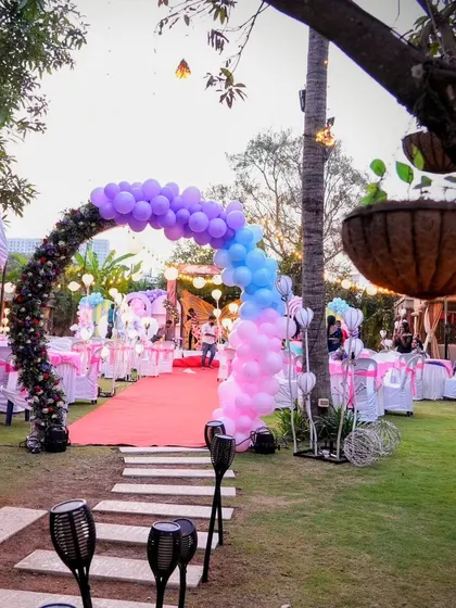 I can transform any space, including beautiful outdoor lawns. This setup shows a grand entrance with a colorful balloon arch leading to an elegantly decorated garden party, proving that your dream celebration can happen anywhere.