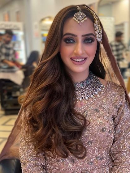 A beautiful bridal portrait. The hair is styled in soft, open waves with a side part, and perfectly accommodates the passa and maang tikka.