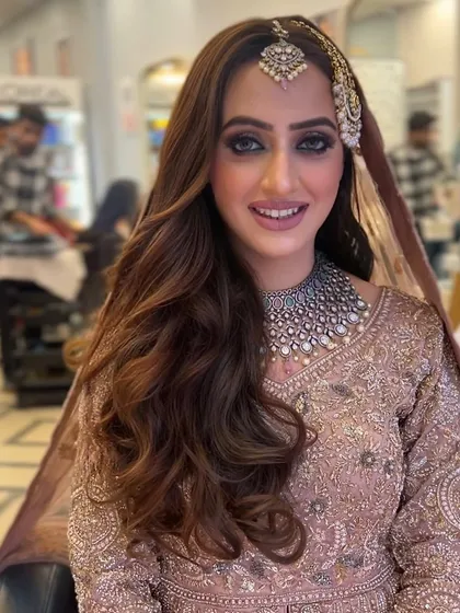 A beautiful bridal portrait. The hair is styled in soft, open waves with a side part, and perfectly accommodates the passa and maang tikka.