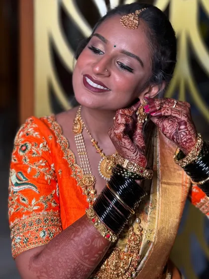 A candid moment of happiness. I love capturing these final touches, where the whole look comes together. This close-up shows the detailed eye makeup, the rich lip color, and the intricate henna, all part of the complete bridal story.