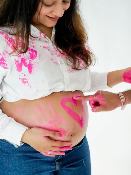 The beginning of a fun gender reveal. A heart is painted on the baby bump, hinting at the colorful surprise to come.