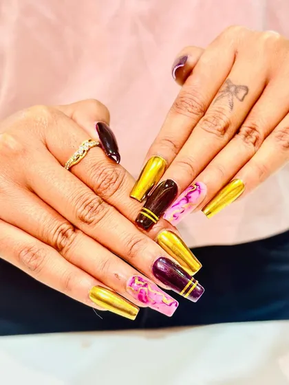 A bold and artistic set combining gold chrome, deep maroon, and pink marble nails.