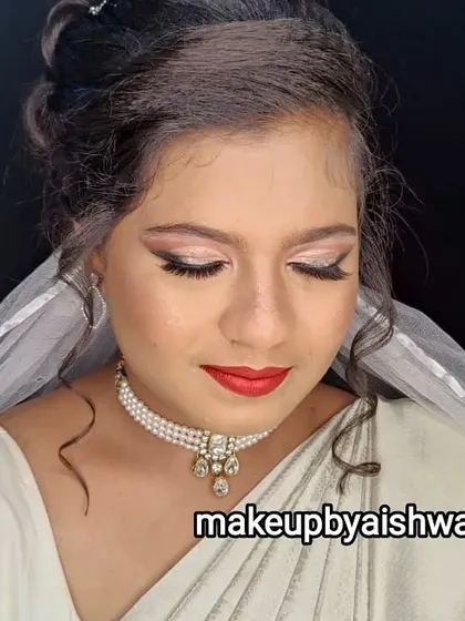 This is an elegant Christian bridal look I created for a white saree ceremony. The makeup is soft and glowing, with shimmery champagne eyeshadow, winged liner, and a classic red lip, complemented by a delicate pearl necklace.