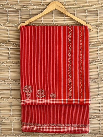 A bright red handloom saree with delicate Chikankari embroidery. The combination of traditional weaving and embroidery creates a stunning piece that celebrates Indian craftsmanship.