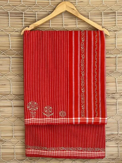 A bright red handloom saree with delicate Chikankari embroidery. The combination of traditional weaving and embroidery creates a stunning piece that celebrates Indian craftsmanship.