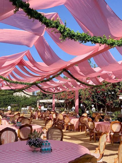 The dining area for the morning wedding, with a scalloped ceiling of pink fabric providing shade and creating a beautiful, soft light.