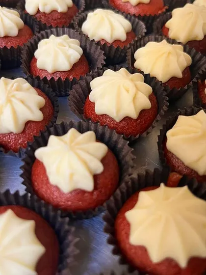 A close-up of our classic mini red velvet cupcakes with a simple, elegant swirl of cream cheese frosting. They are a timeless favorite for any event.