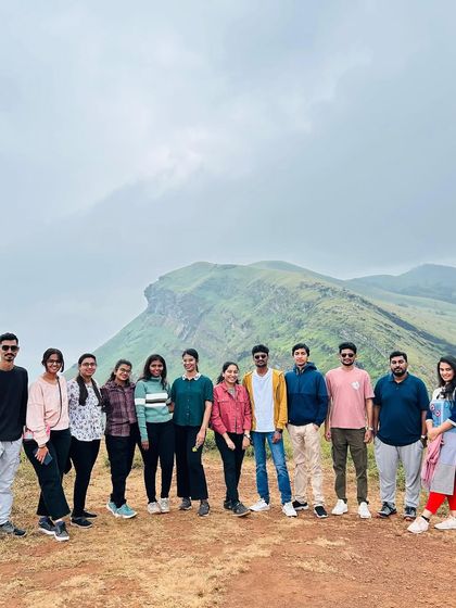 The group posing on the trail, with the unique shape of the Chikmagalur peaks behind them.