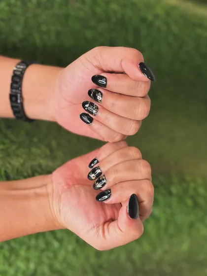 This edgy design features a glossy black polish with shattered gold and silver foil accents. The almond nail shape keeps the look sharp and modern.