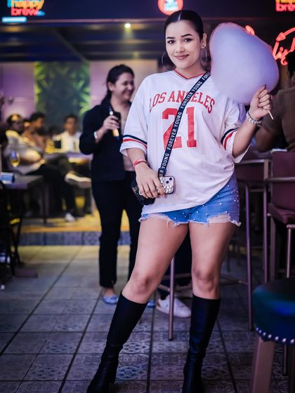 A guest enjoying the pink-themed decor and complimentary cotton candy. The entire venue is transformed to fit the 'Girls Night Out' theme every Tuesday.