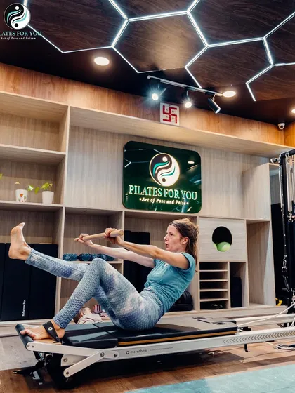 This client is using the push-through bar on the reformer for a full-body exercise that strengthens the core and improves coordination. The studio's calming ambiance enhances focus.