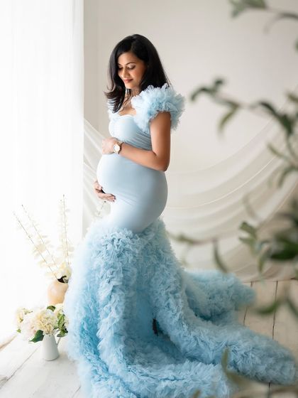 Another look at this incredible blue gown, this time with the mom-to-be standing by the window, allowing the natural light to beautifully illuminate her and the dress.