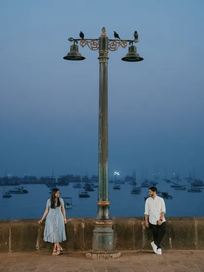 The magic of Mumbai at dusk provides a cinematic setting for romance. This shot at the Gateway of India uses the moody blue hour and iconic lamppost to frame the couple, creating a sense of quiet intimacy within the bustling city.