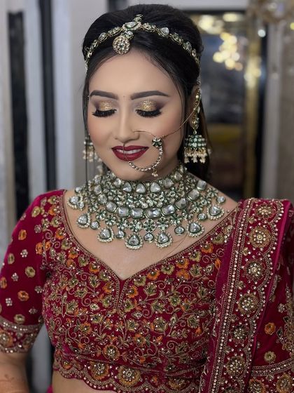 The complete look. This image shows the beautiful harmony between the makeup, the red velvet lehenga, and the heavy bridal jewelry, creating a look of pure regality.
