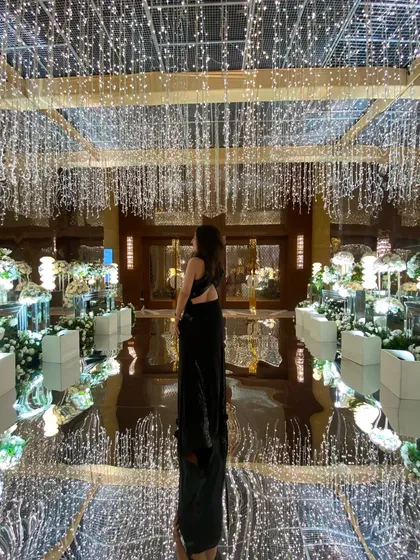 Dressed in a black gown for a cocktail event, surrounded by magical fairy lights. This look is all about midnight charm and glamour.